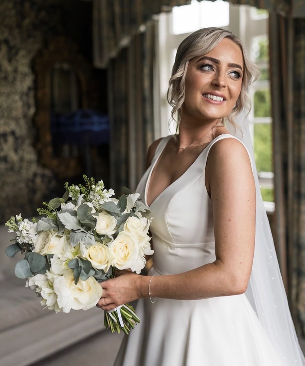 A bride’s soft blonde up-do, loose curls around the face.